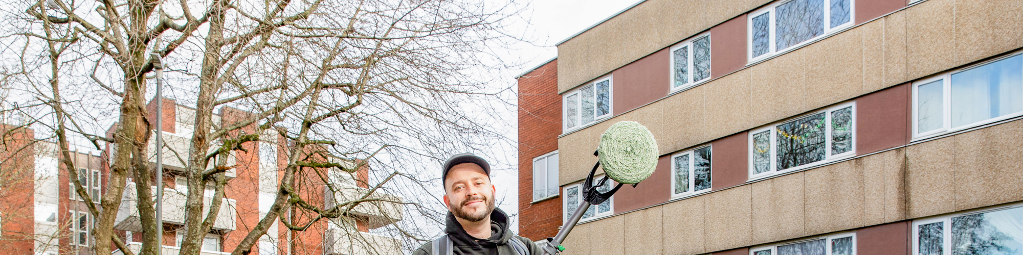 Bromford colleague holding new graffiti removing machine in front of blocks of flats in Bristol
