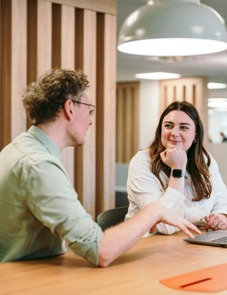 Two people sat at a desk talking