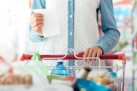 Woman shopping with trolley and list