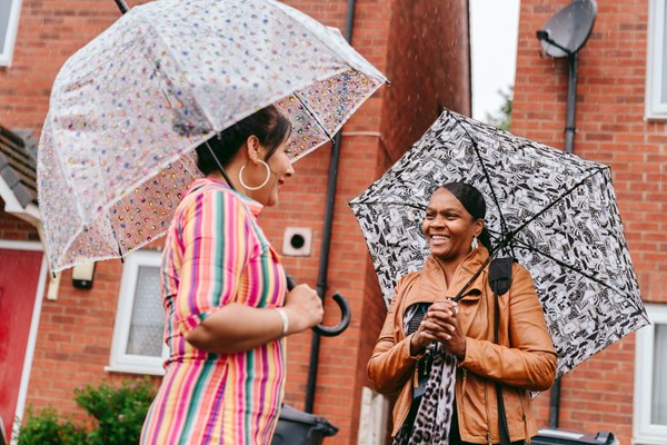 Neighbourhood coach talks to a customer under umbrellas