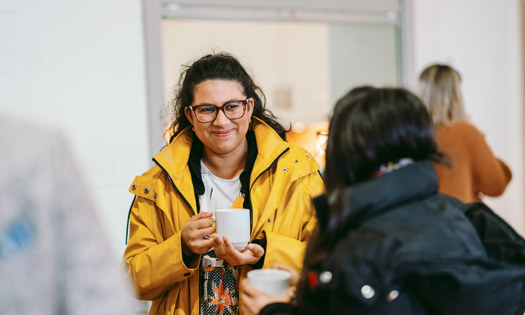Two people in conversation holding mugs 