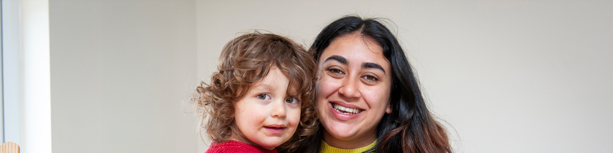 A mother and her child stand together holding a white bag of food