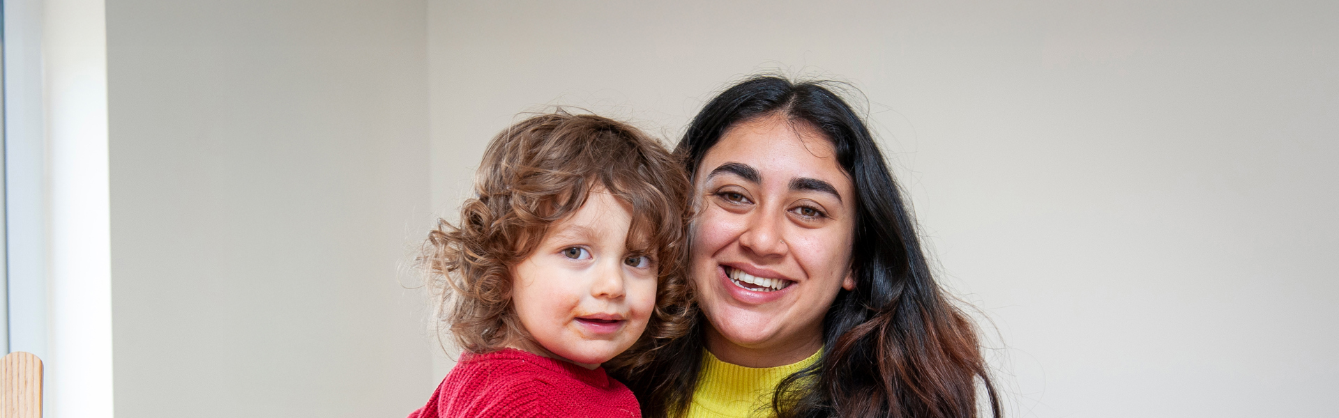 A mother and her child stand together holding a white bag of food