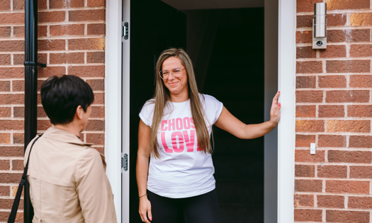 customer standing with neighbourhood coach in doorway to home