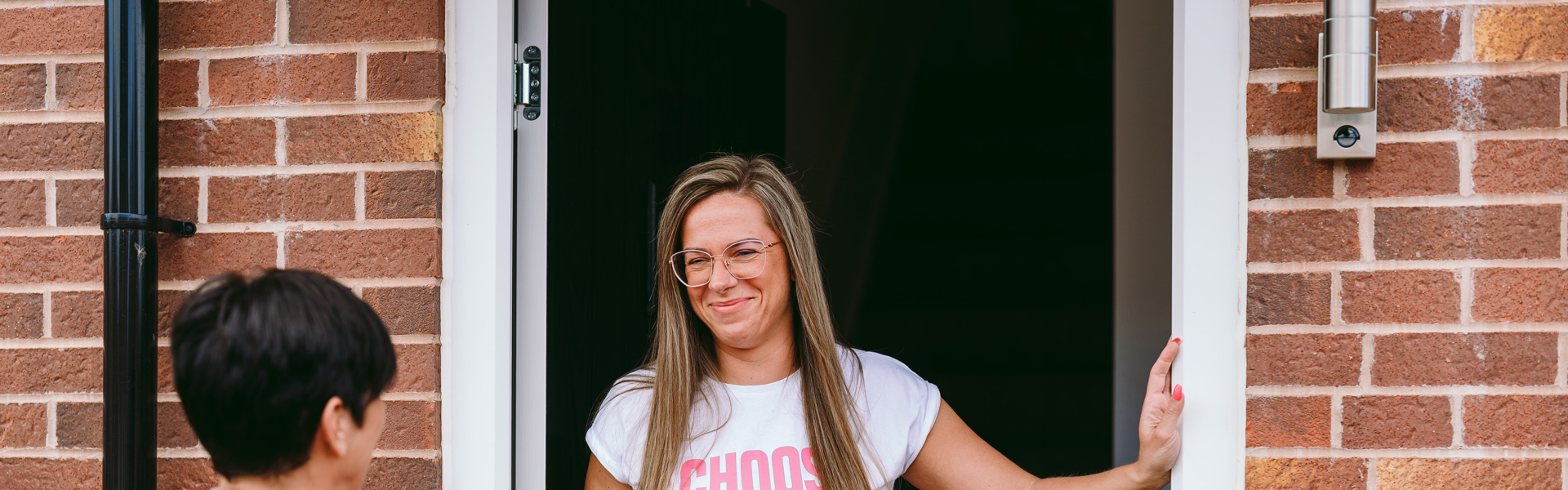 customer standing with neighbourhood coach in doorway to home