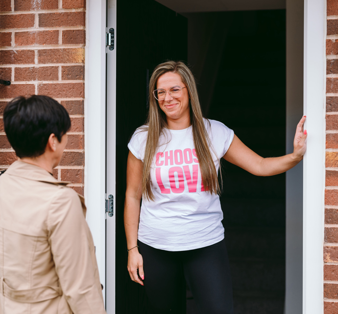 customer standing with neighbourhood coach in doorway to home