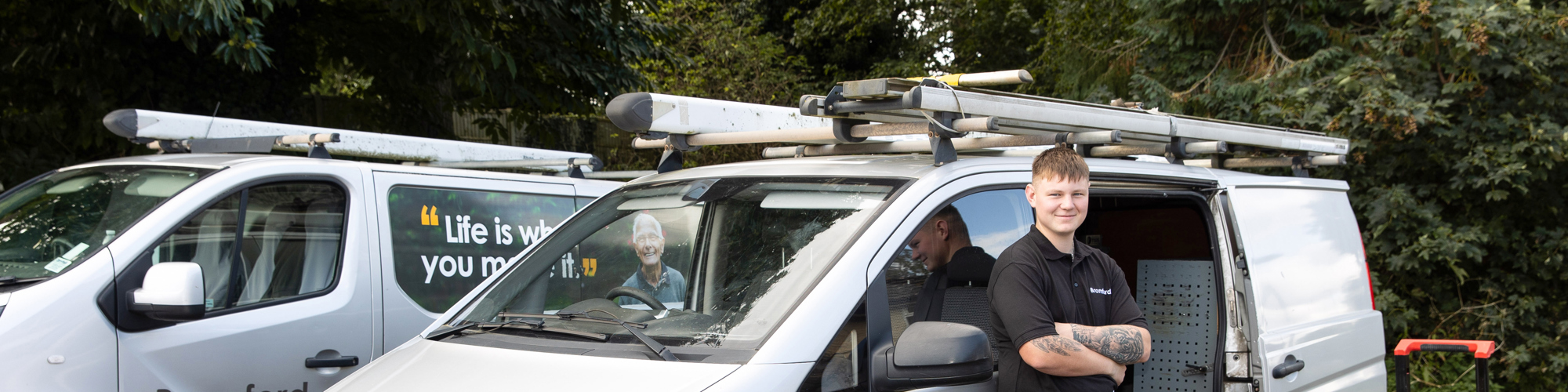 Bromford colleague smiling and standing in front of a Bromford van 