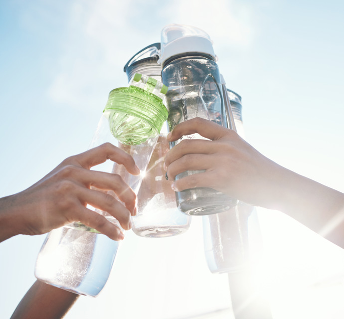 Four hands toasting four water bottles 