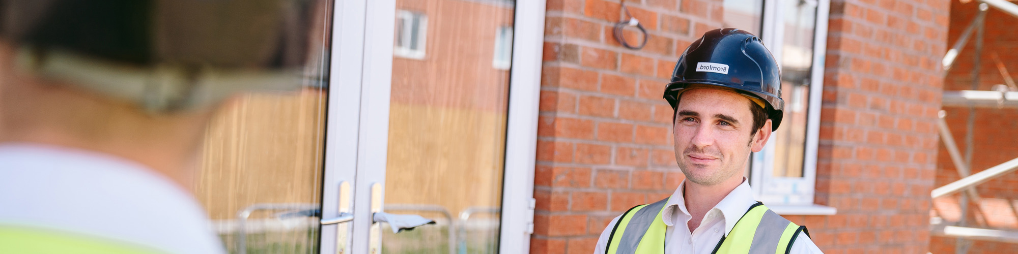 Person wearing a hard hat on holding a clipboard
