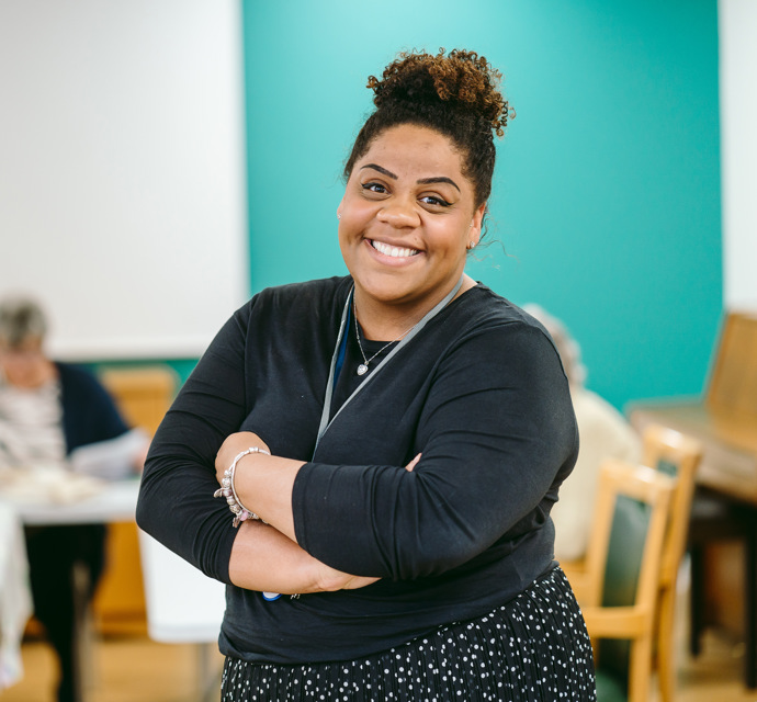 A woman stands with her arms crossed in an art room