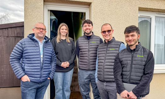 A group of 4 people stand in front of a house doorway - From left to right - Mike Craggs (Bromford), Stacey Ellis (Bromford Customer), Tom Fenton, Jari Söhne and Thomas O' Connor from Senze