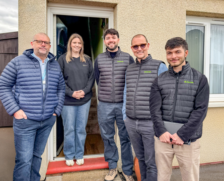 A group of 4 people stand in front of a house doorway - From left to right - Mike Craggs (Bromford), Stacey Ellis (Bromford Customer), Tom Fenton, Jari Söhne and Thomas O' Connor from Senze