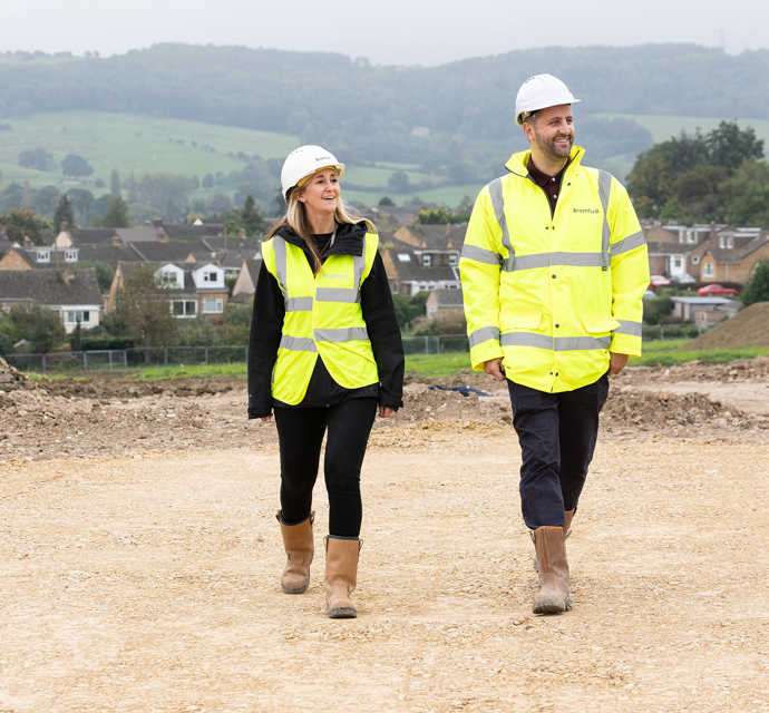 Two bromford colleagues wearing high visability coats, walking on a constructionsite