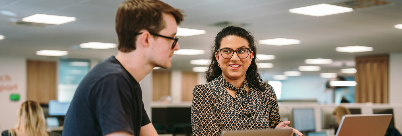 Two people sat at a desk talking
