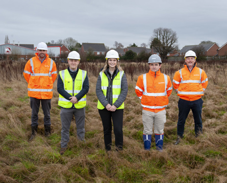 Five people smiling and each wearing a high-vis