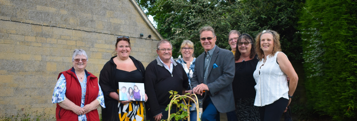 People standing in front of a rose which they planted 